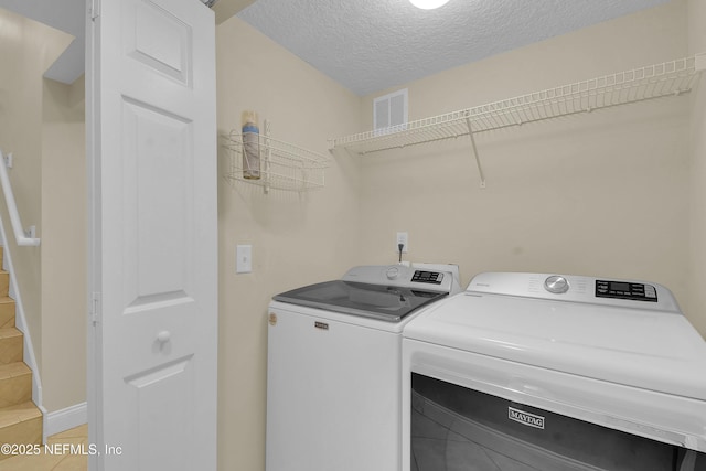 laundry area with washer and clothes dryer and a textured ceiling