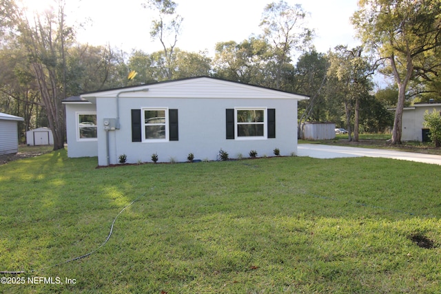 ranch-style home featuring an outdoor structure, a storage unit, a front lawn, and stucco siding