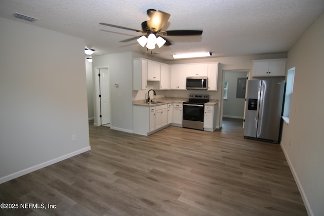 kitchen with white cabinets, appliances with stainless steel finishes, light countertops, and wood finished floors