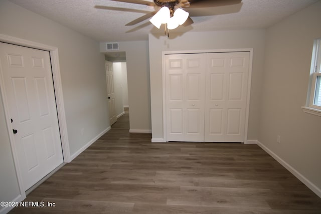 unfurnished bedroom with visible vents, a textured ceiling, a closet, and wood finished floors