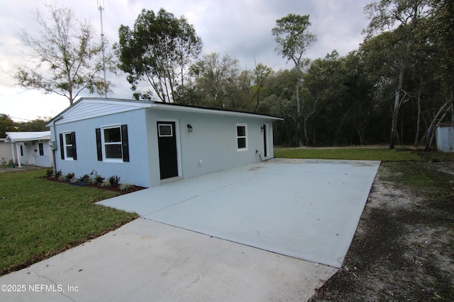 exterior space with stucco siding and a front yard