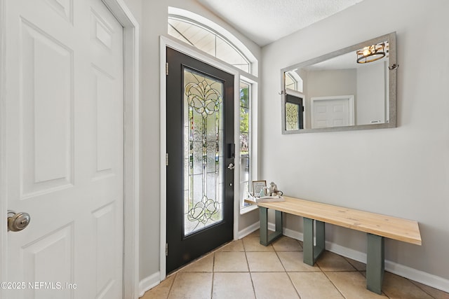 foyer featuring baseboards, plenty of natural light, a textured ceiling, and tile patterned flooring