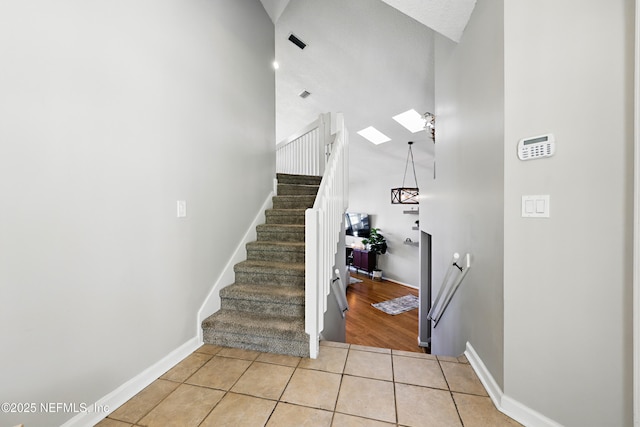 stairway with tile patterned floors, a skylight, baseboards, and visible vents