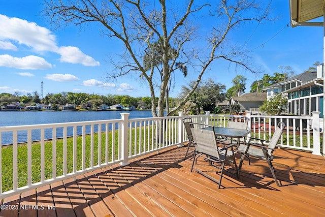 wooden terrace featuring outdoor dining space and a water view