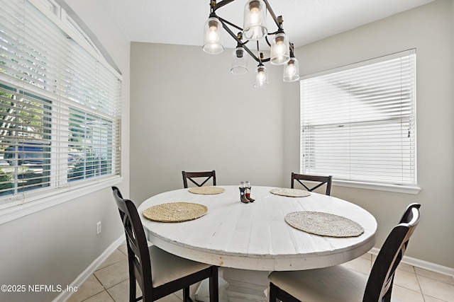 dining area with a chandelier, baseboards, and light tile patterned flooring