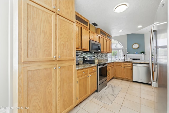 kitchen featuring visible vents, light stone counters, appliances with stainless steel finishes, light tile patterned flooring, and decorative backsplash