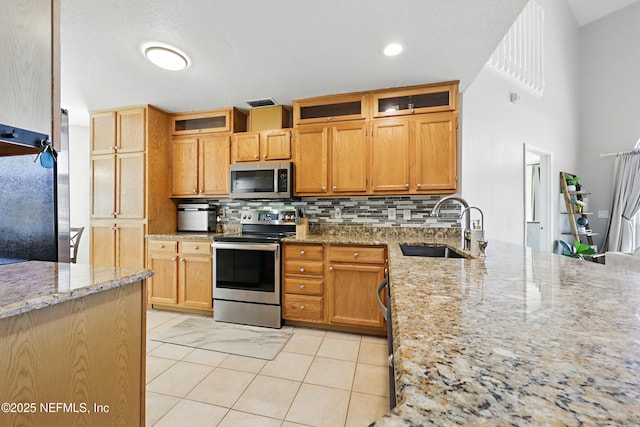 kitchen with light stone counters, visible vents, a sink, decorative backsplash, and stainless steel appliances