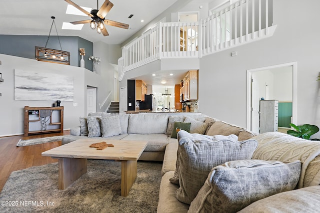 living room featuring ceiling fan, stairway, recessed lighting, a skylight, and wood finished floors