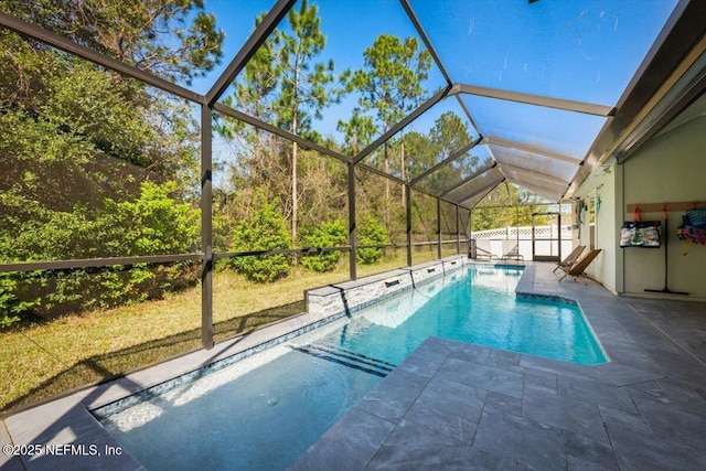 outdoor pool featuring glass enclosure and a patio