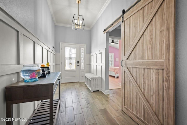 entrance foyer with a barn door, wood finished floors, crown molding, and a decorative wall