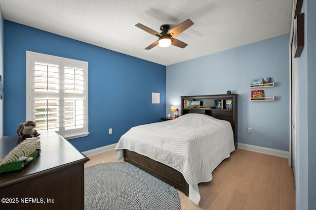 bedroom featuring ceiling fan, a textured ceiling, baseboards, and wood finished floors