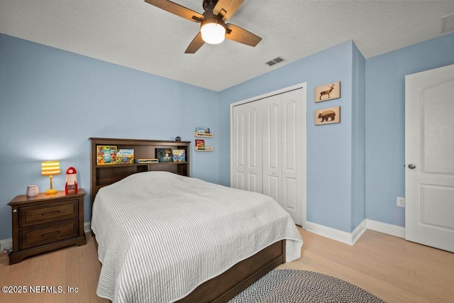 bedroom with visible vents, ceiling fan, baseboards, wood finished floors, and a closet