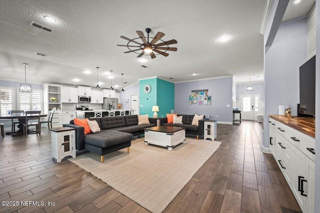 living room featuring a textured ceiling, ceiling fan, dark wood-style flooring, and crown molding