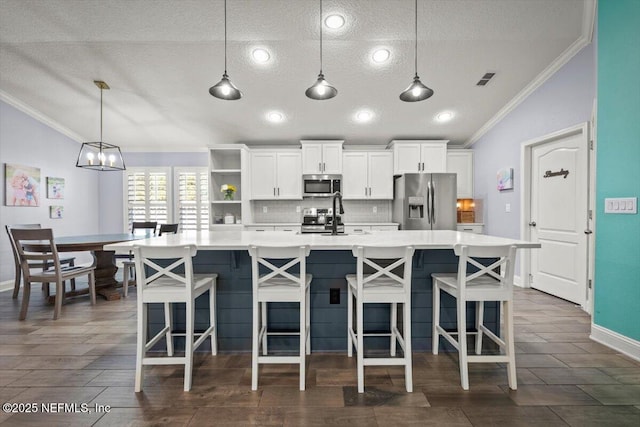 kitchen with a spacious island, decorative backsplash, appliances with stainless steel finishes, and lofted ceiling