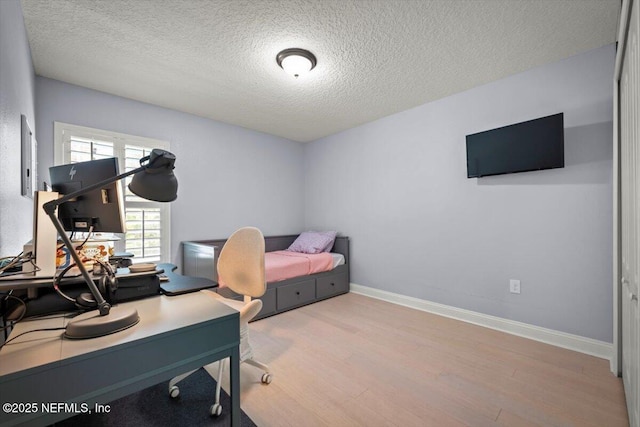 bedroom featuring wood finished floors, baseboards, and a textured ceiling