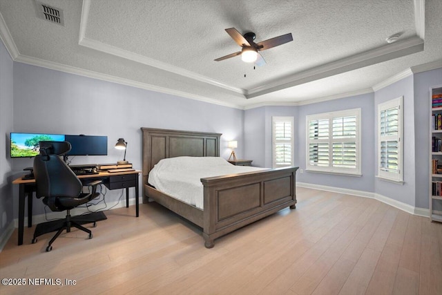 bedroom with light wood-type flooring, visible vents, and a raised ceiling