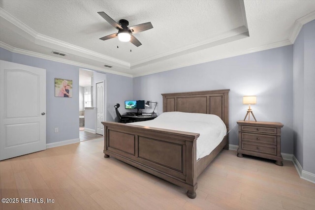 bedroom with a tray ceiling, a textured ceiling, visible vents, and light wood finished floors