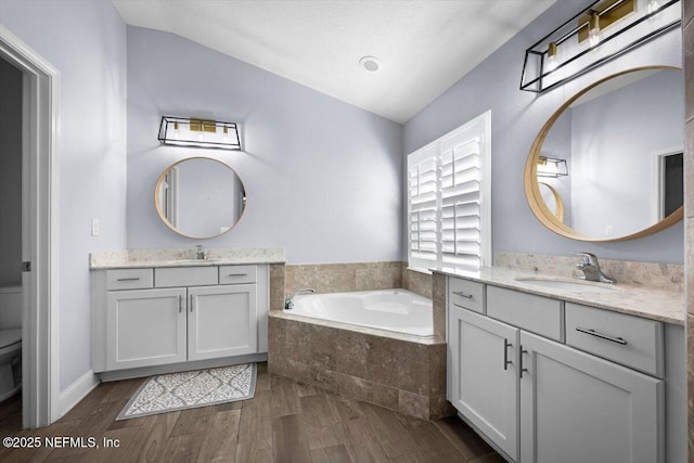 bathroom featuring a sink, a garden tub, wood finished floors, and toilet