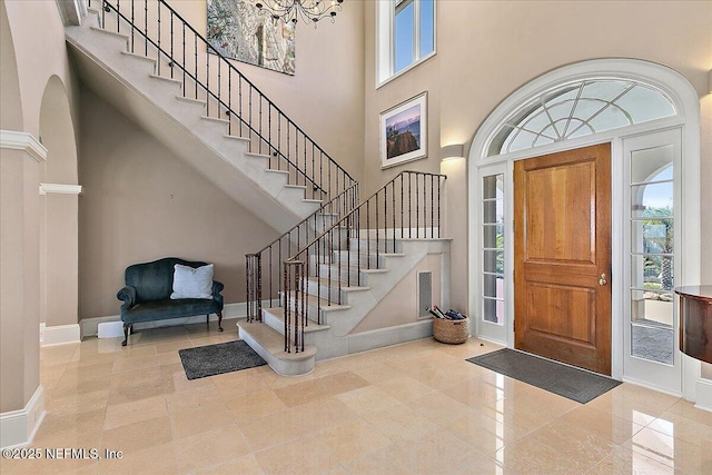 entrance foyer with stairway, an inviting chandelier, a high ceiling, and baseboards