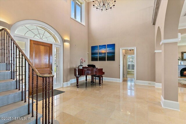 foyer with a chandelier, plenty of natural light, stairs, and baseboards