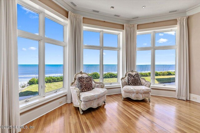 living area featuring a water view, light wood finished floors, and ornamental molding