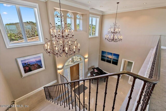 stairway with a notable chandelier, baseboards, and ornamental molding