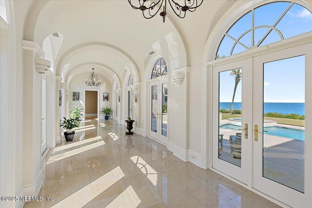 interior space with baseboards, french doors, a towering ceiling, a notable chandelier, and marble finish floor