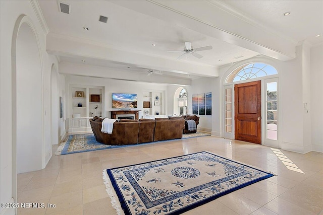 living room with visible vents, built in shelves, baseboards, a fireplace, and arched walkways