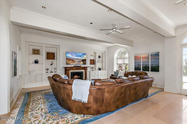 living area with crown molding, a warm lit fireplace, built in features, and a wealth of natural light