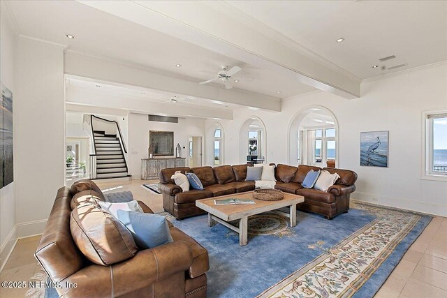 living area with crown molding, baseboards, and arched walkways