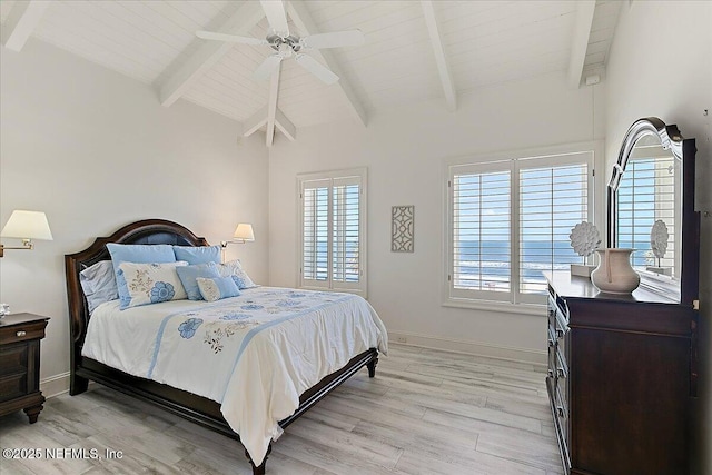 bedroom featuring multiple windows, lofted ceiling with beams, and light wood-style floors