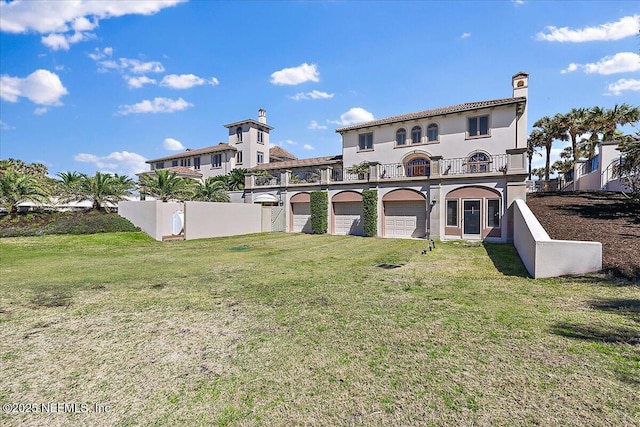 back of property featuring a lawn, driveway, a balcony, and fence