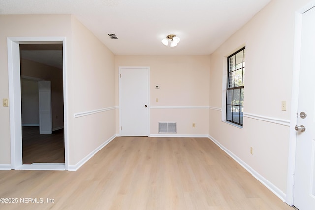 unfurnished room with visible vents, light wood-type flooring, and baseboards