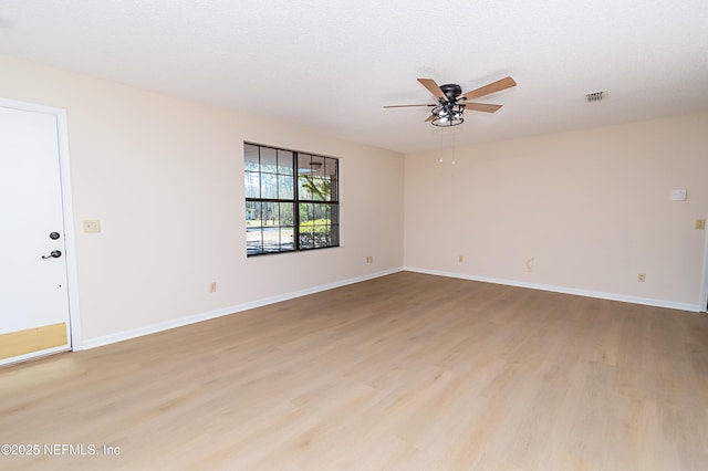 spare room featuring baseboards and light wood finished floors