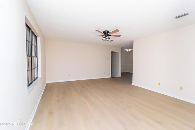 unfurnished room featuring a ceiling fan, baseboards, visible vents, and light wood finished floors