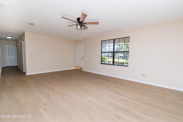 spare room with a ceiling fan, visible vents, baseboards, light wood-style floors, and a textured ceiling