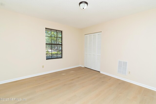 spare room featuring baseboards, visible vents, and light wood-type flooring