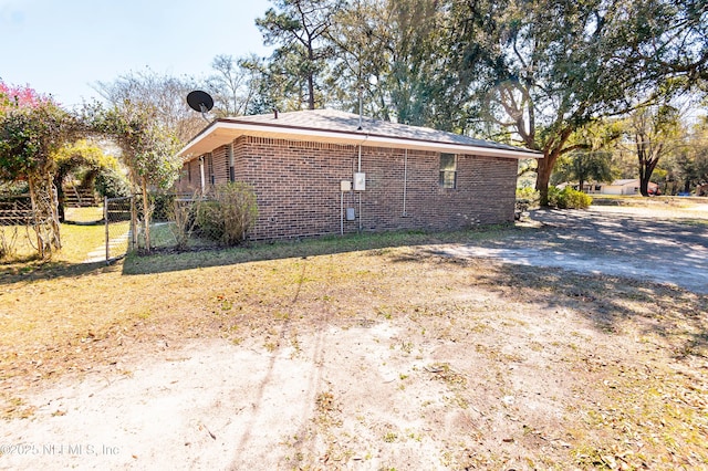 view of property exterior featuring fence and brick siding