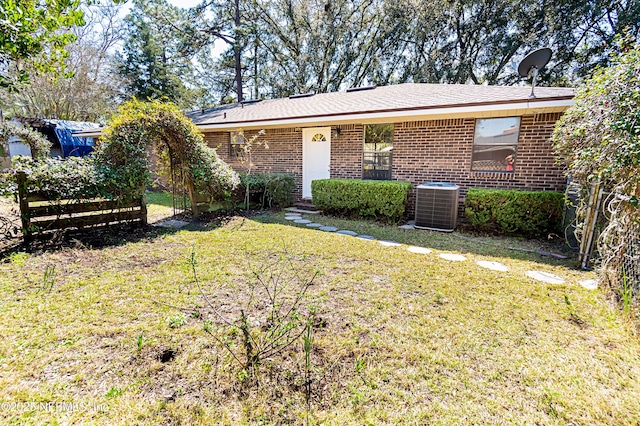 ranch-style house featuring cooling unit, brick siding, and a front lawn