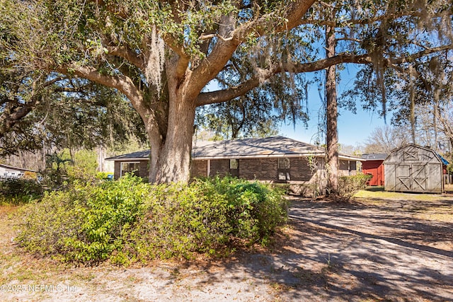 view of front of property with a storage shed, brick siding, and an outdoor structure