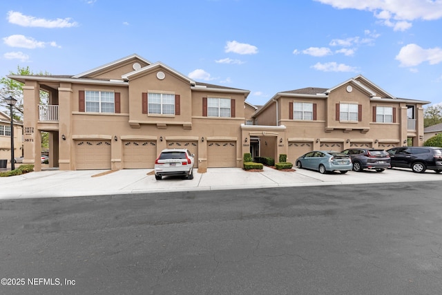 townhome / multi-family property featuring a garage, driveway, and stucco siding