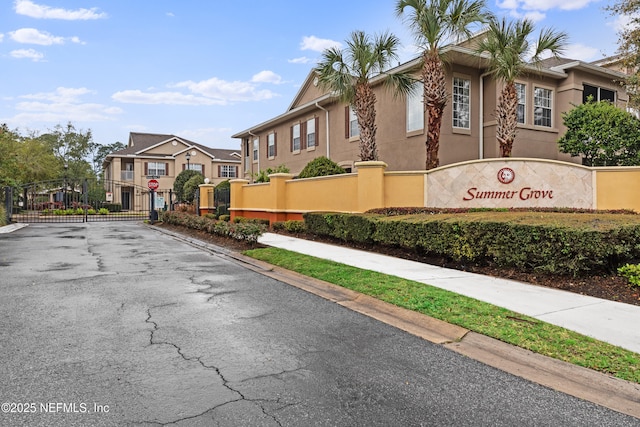 view of street featuring traffic signs, curbs, a gate, a gated entry, and a residential view