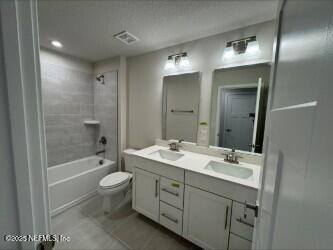 bathroom with bathtub / shower combination, double vanity, toilet, and a sink