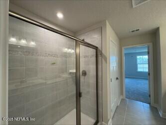 bathroom with tile patterned floors, mail area, a stall shower, and visible vents