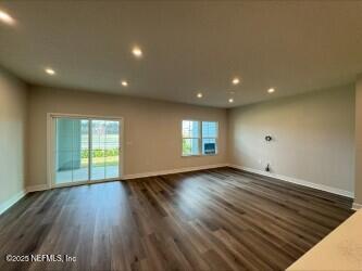 unfurnished living room with recessed lighting, a healthy amount of sunlight, dark wood-type flooring, and baseboards