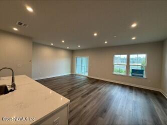 unfurnished living room featuring visible vents, recessed lighting, dark wood-type flooring, and baseboards