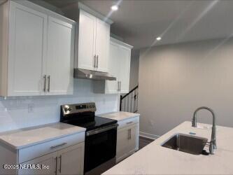 kitchen featuring stainless steel electric range oven, a sink, light countertops, white cabinets, and under cabinet range hood