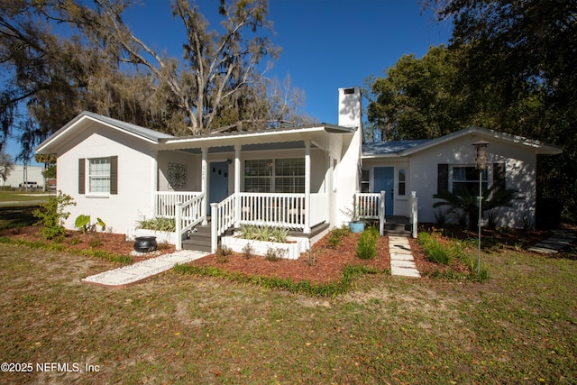 ranch-style home with a porch, a chimney, and a front yard