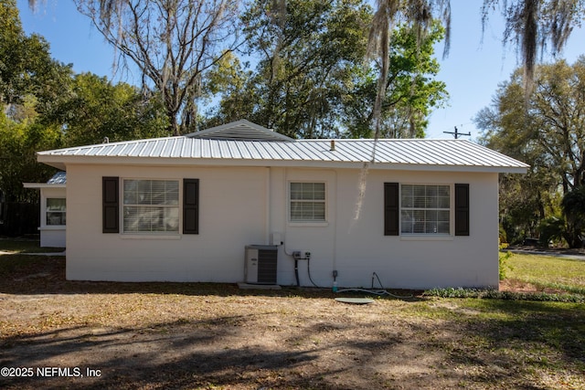 rear view of house with metal roof, concrete block siding, and central AC