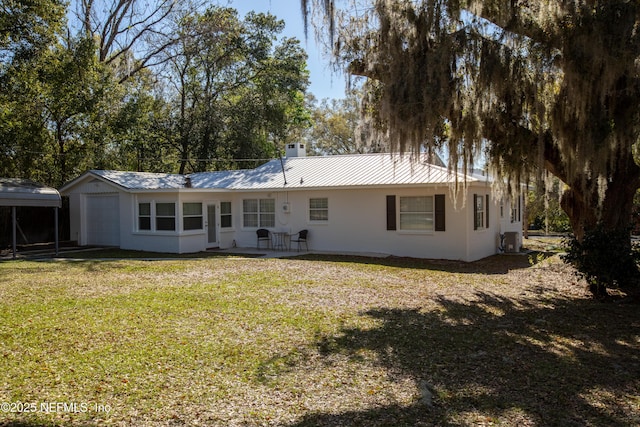 back of house featuring a yard, central AC unit, and metal roof